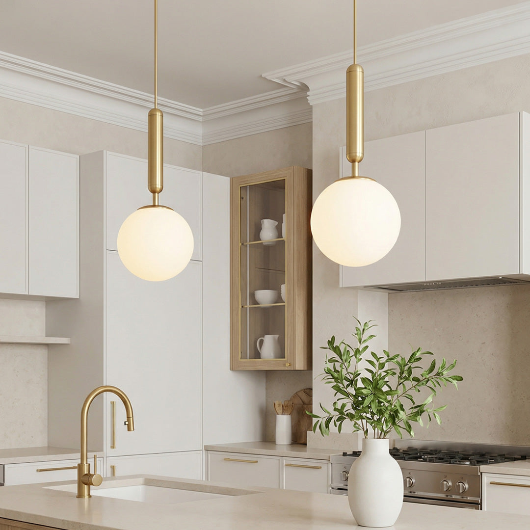 Modern gold hanging lights with frosted glass globes over a bright marble kitchen island desk.