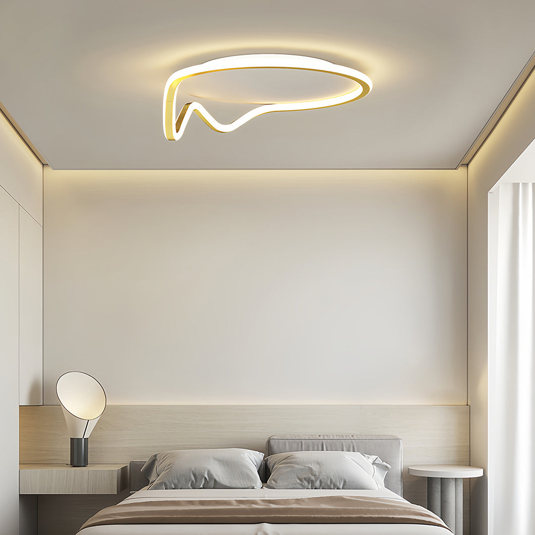 Modern gold and white abstract geometric flush mount light fixture installed in a minimalist bedroom with soft lighting.