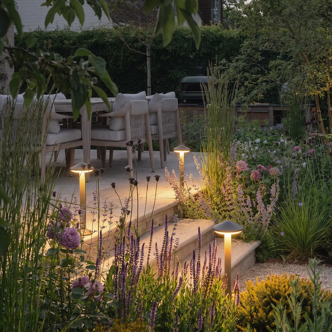 Modern gray mushroom path lights illuminating stone steps leading to an outdoor garden dining area