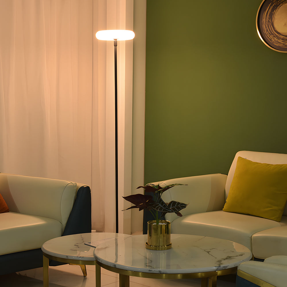 Modern halo floor lamp with sleek black pillar and circular LED top providing warm ambient lighting in contemporary living room