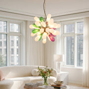 Modern large chandelier with colorful glass shades installed in a bright living room with floor-to-ceiling windows.