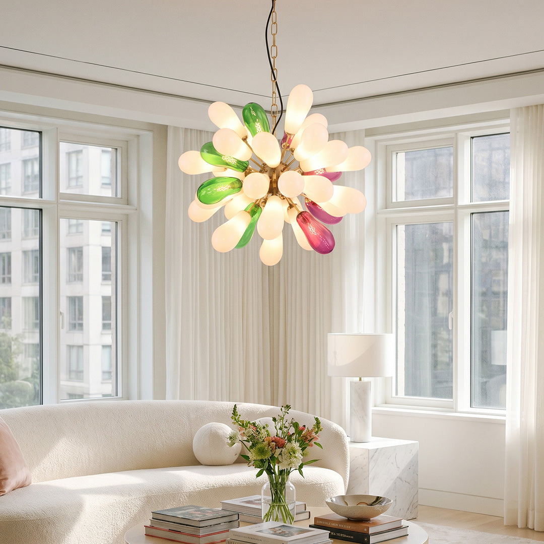 Modern large chandelier with colorful glass shades installed in a bright living room with floor-to-ceiling windows.