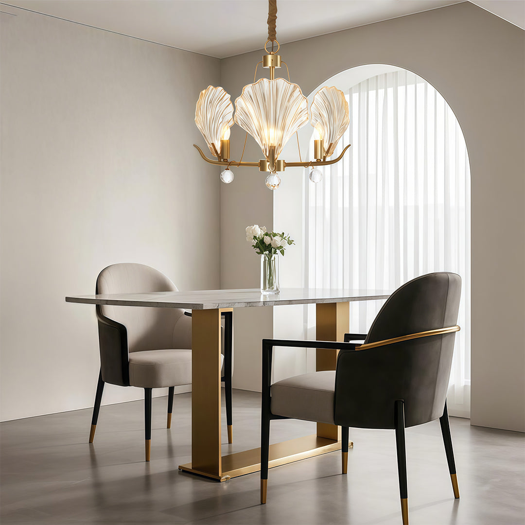 Modern large chandeliers illuminating sophisticated dining room with round table and velvet chairs