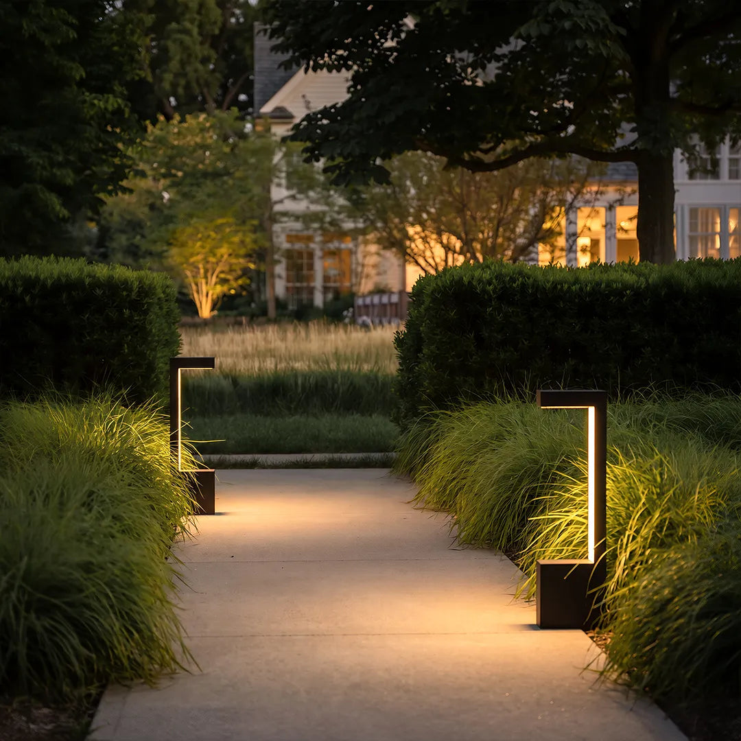 Modern LED bollard lights illuminating garden walkway with lush green landscaping