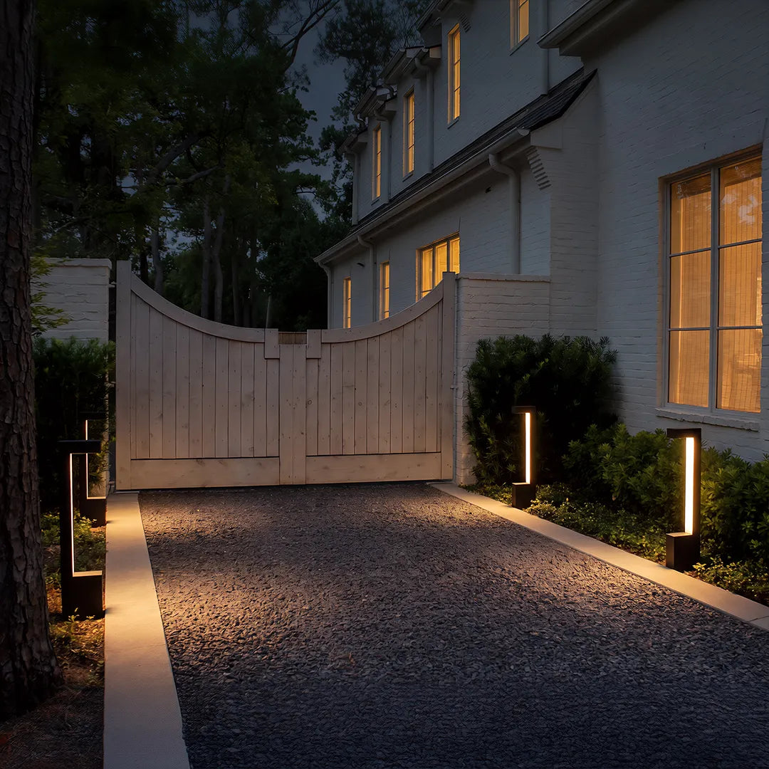 Modern LED bollard lights with warm glow along residential gravel driveway