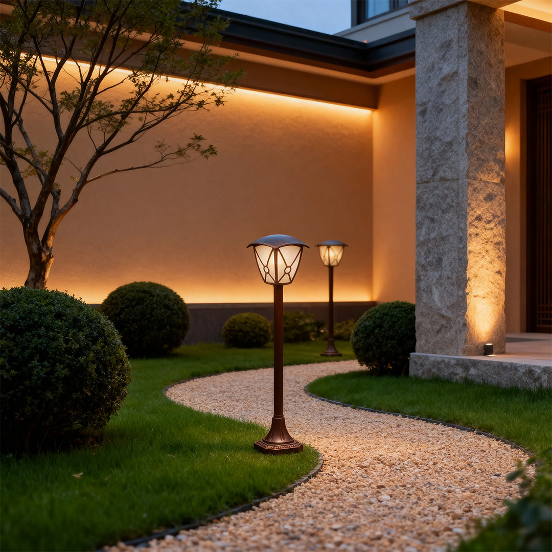 Modern LED fence bollard light illuminating gravel pathway beside contemporary home at twilight