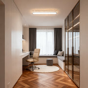 Modern LED flush mount light fixture featuring glass shade chandelier aesthetic in bright bedroom with wood herringbone flooring.