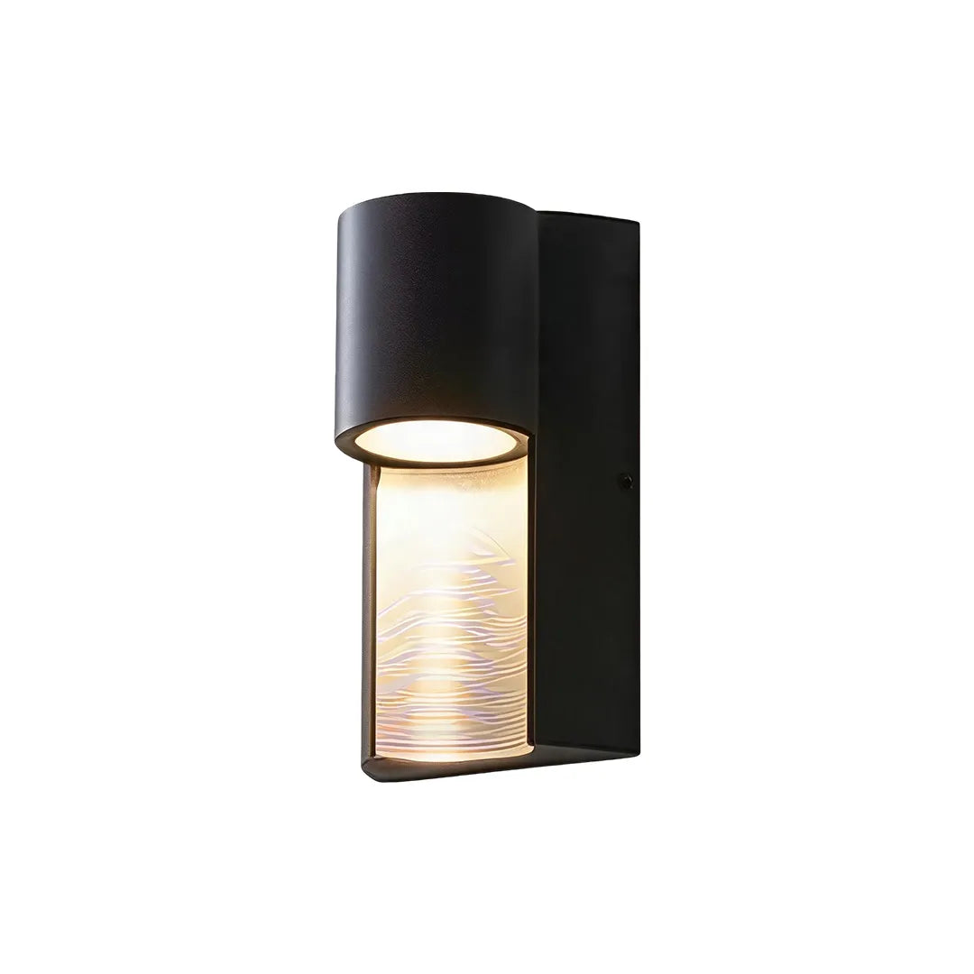 Modern LED outdoor wall light with a black cylindrical shade and textured illuminated glass diffuser.
