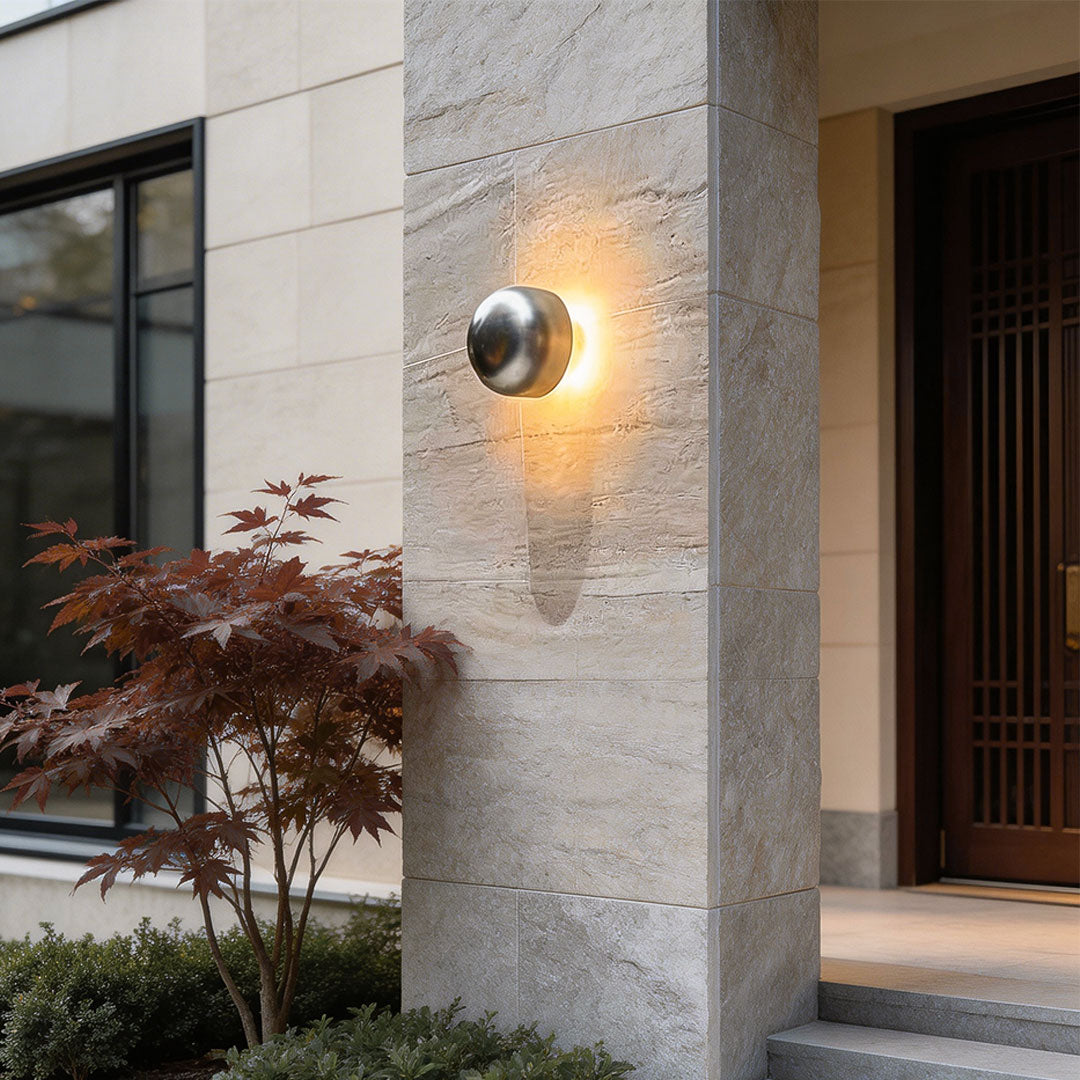 Close-up of a modern LED outdoor wall light with a curved black design and warm glow.