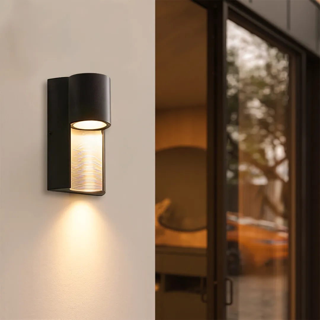 Modern LED outdoor wall light casting focused downward illumination beside a modern doorway.