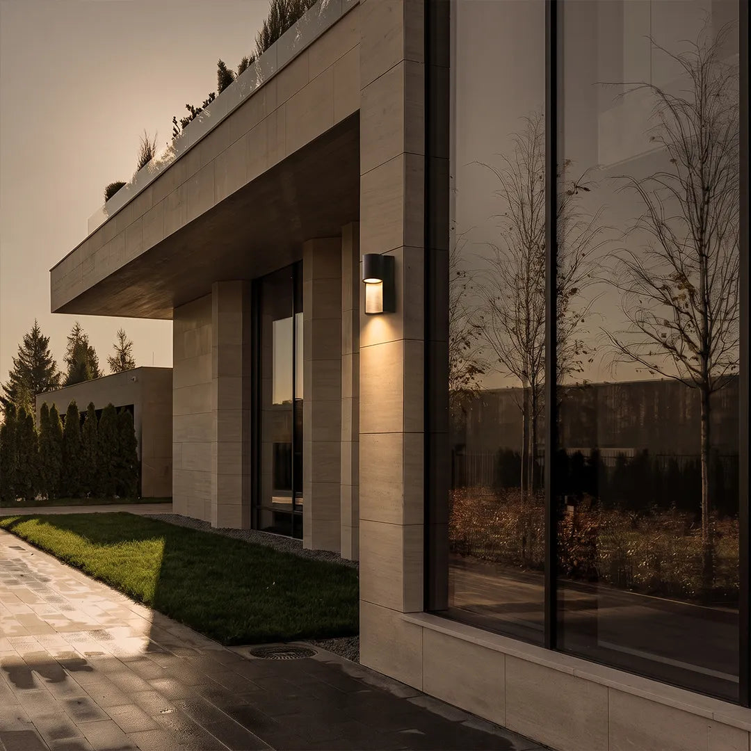 Modern LED outdoor wall light installed beside large glass doors on a contemporary exterior wall.