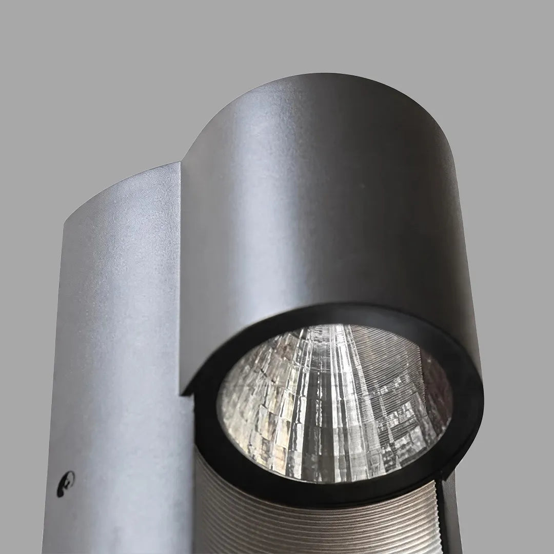 Modern LED outdoor wall light close-up showing the black cylindrical housing and reflective LED interior.