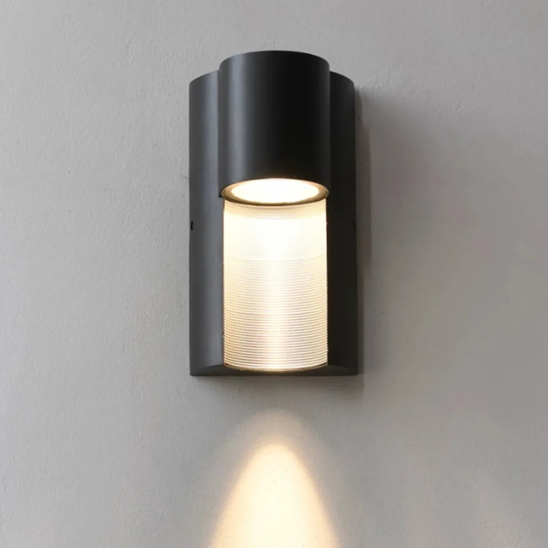 Modern LED outdoor wall light shown illuminated with a black curved housing and textured glass panel.