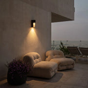 Modern LED outdoor wall light casting a warm downward beam across a contemporary patio wall.