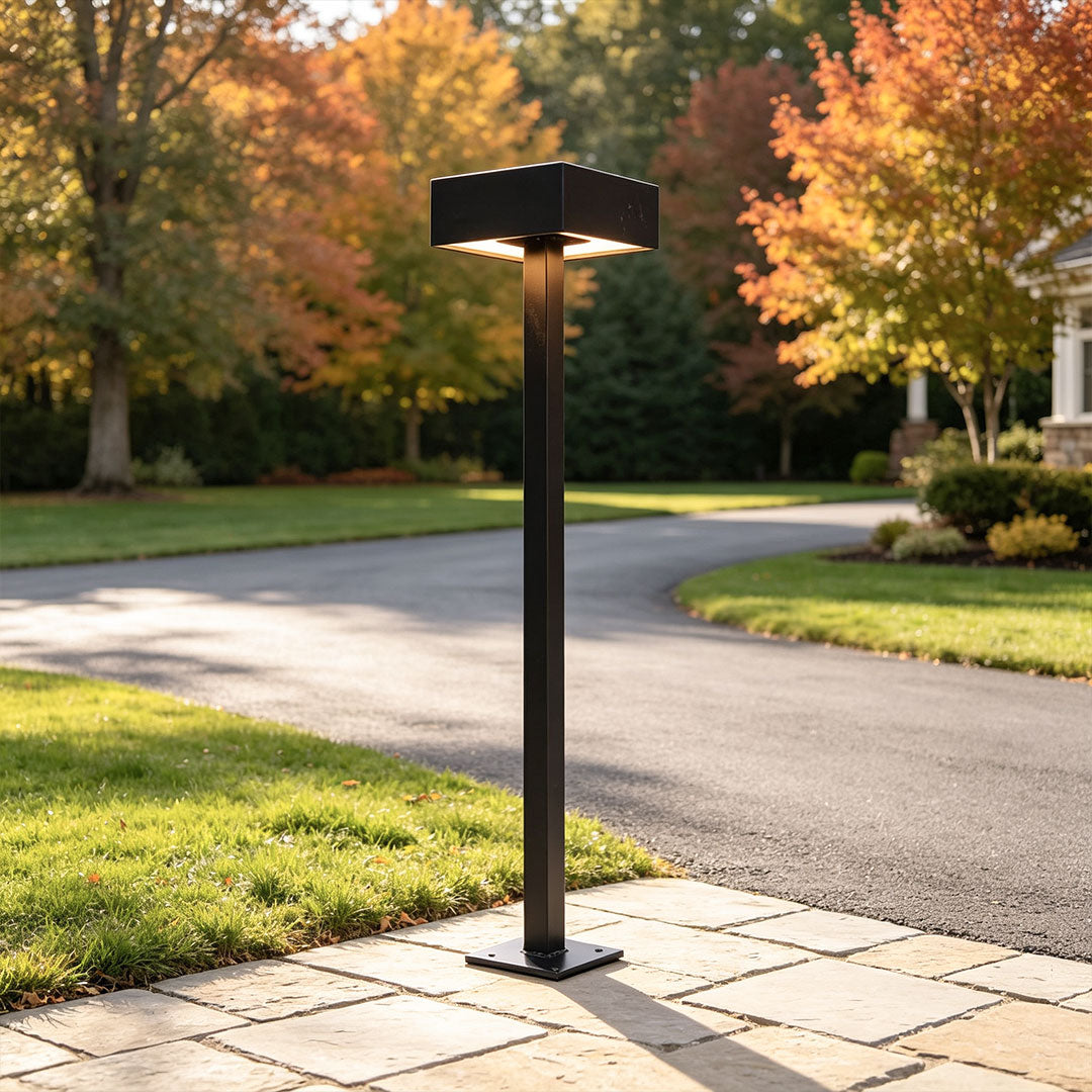 Modern LED path lights illuminating residential driveway landscaping with sleek black outdoor bollard design.