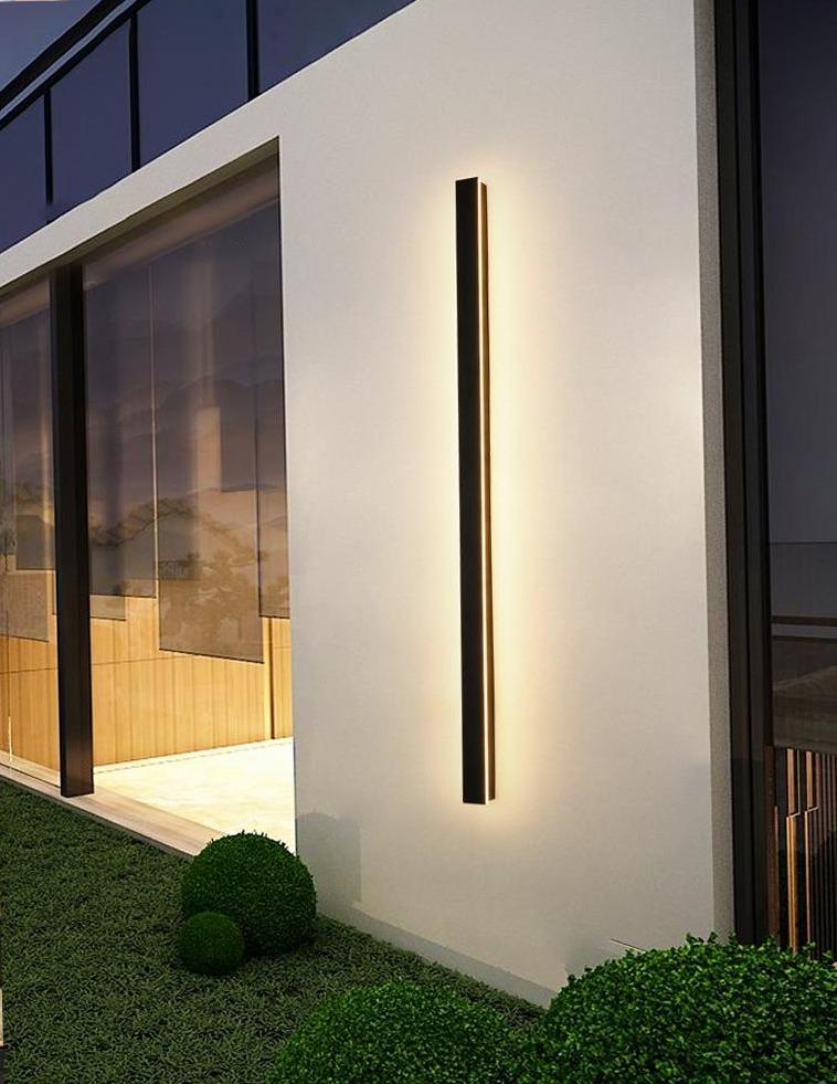 Modern linear outdoor wall sconce emitting soft glow, perfectly integrated into minimalist stone architecture.