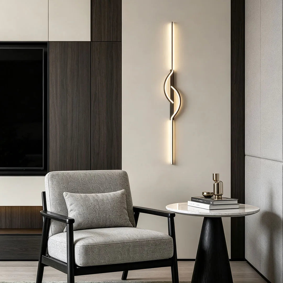 Modern linear wall sconce placed beside a lounge chair in a minimalist interior with warm ambient lighting.