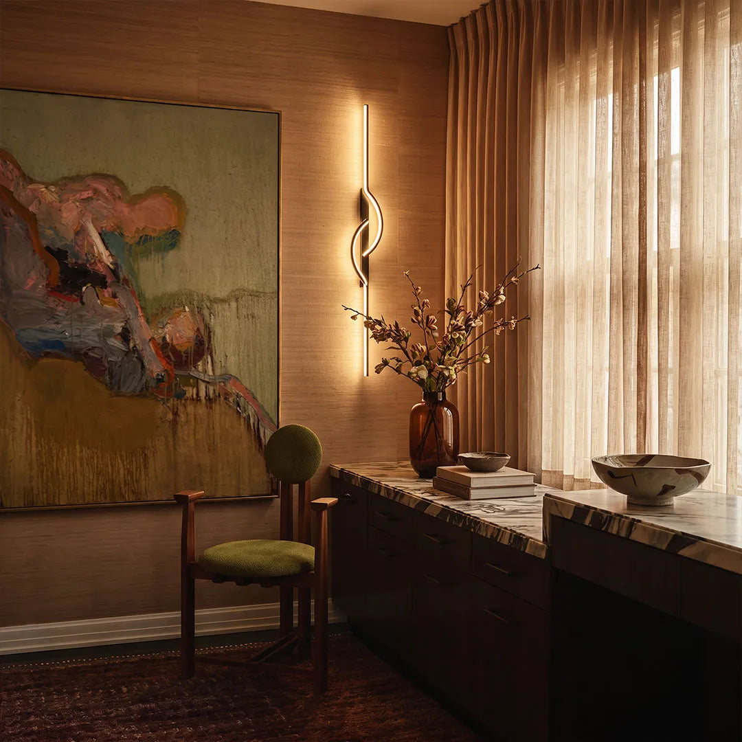 Modern linear wall sconce mounted on a wood accent wall above a console table in a stylish interior.