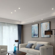 Modern living room ceiling with recessed modern spotlights illuminating a white sofa and blue wall art.