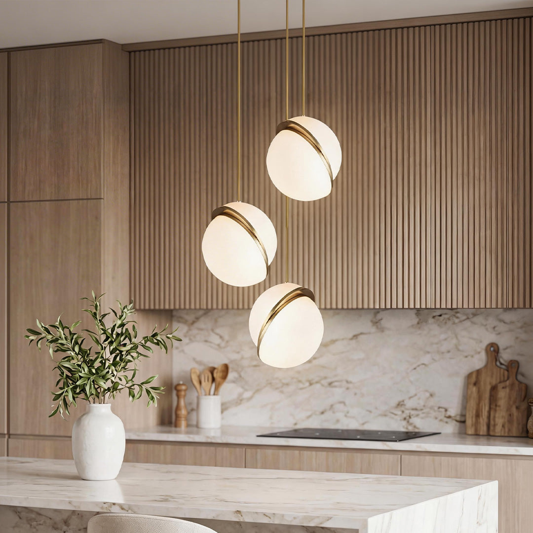 Elegant White Spherical Pendant Light with gold trim over a marble island in a modern kitchen.