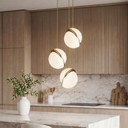 Elegant White Spherical Pendant Light with gold trim over a marble island in a modern kitchen.