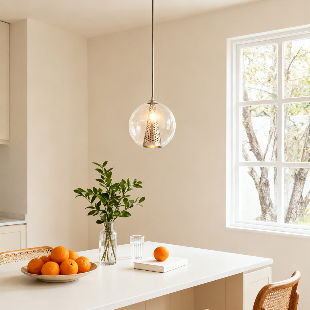 Modern minimalist glass ball pendant lights suspended over a white kitchen table, complementing the bright, airy contemporary space.