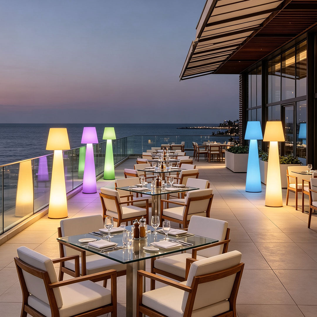 Modern minimalist floor lamps glowing in multiple colors beside a luxury rooftop dining area.