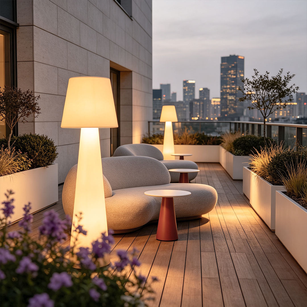 Modern minimalist floor lamp beside a rooftop lounge with warm decorative outdoor illumination.