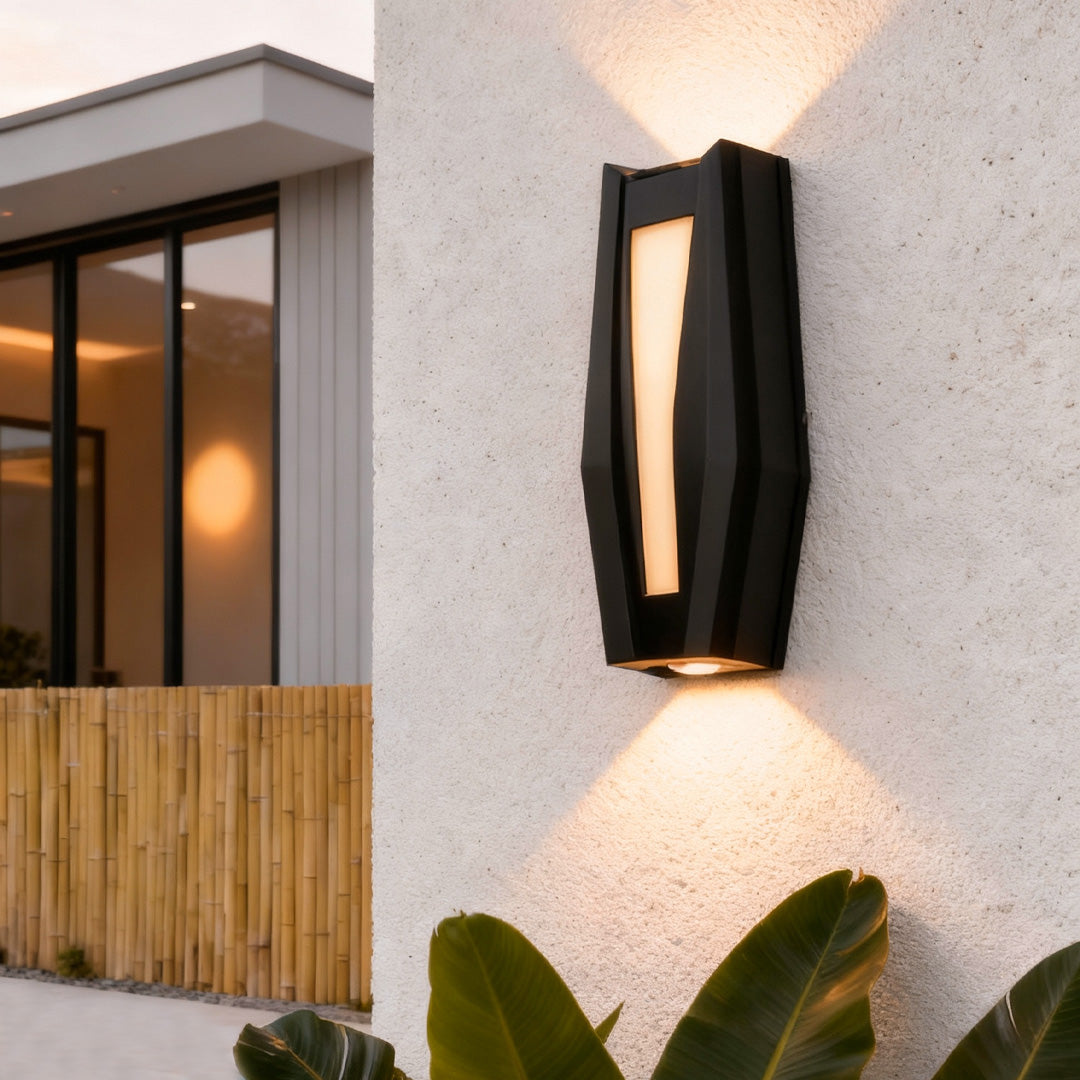 Warm glowing up down outdoor wall light mounted near large windows in a modern outdoor area.