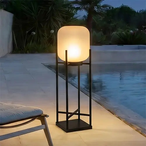 Modern outdoor floor lamp beside a swimming pool at night