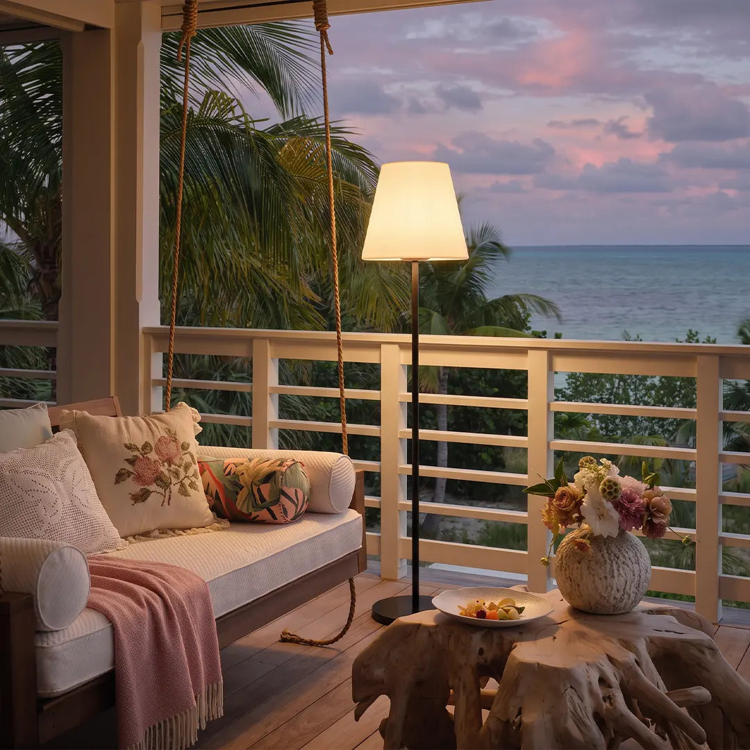 Modern outdoor floor lamp illuminating a covered balcony lounge with an ocean view.