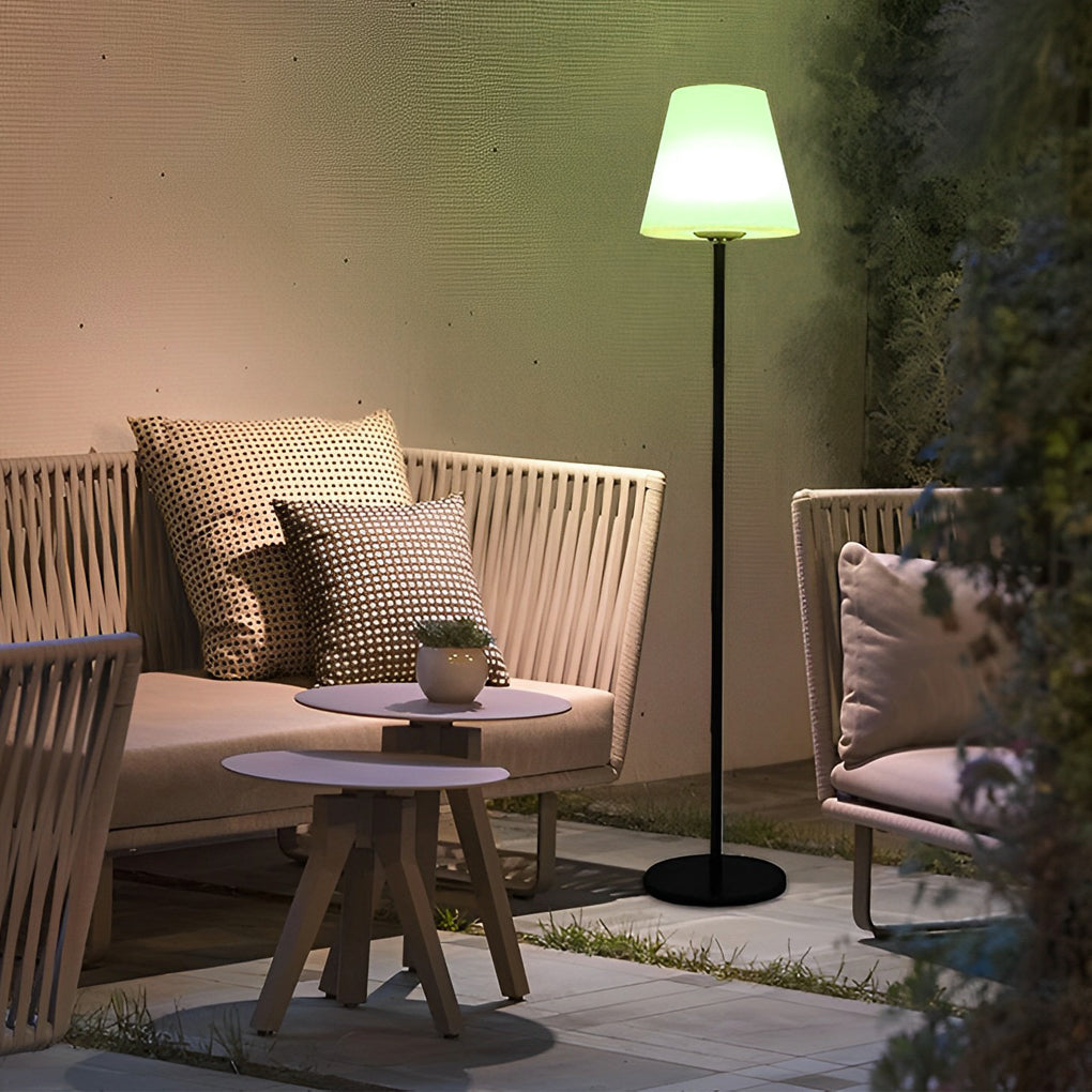 Modern outdoor floor lamp illuminating a cozy outdoor sofa setup with cushions and a side table.