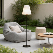 Modern outdoor floor lamp beside a lounge chair on a cozy patio seating area.