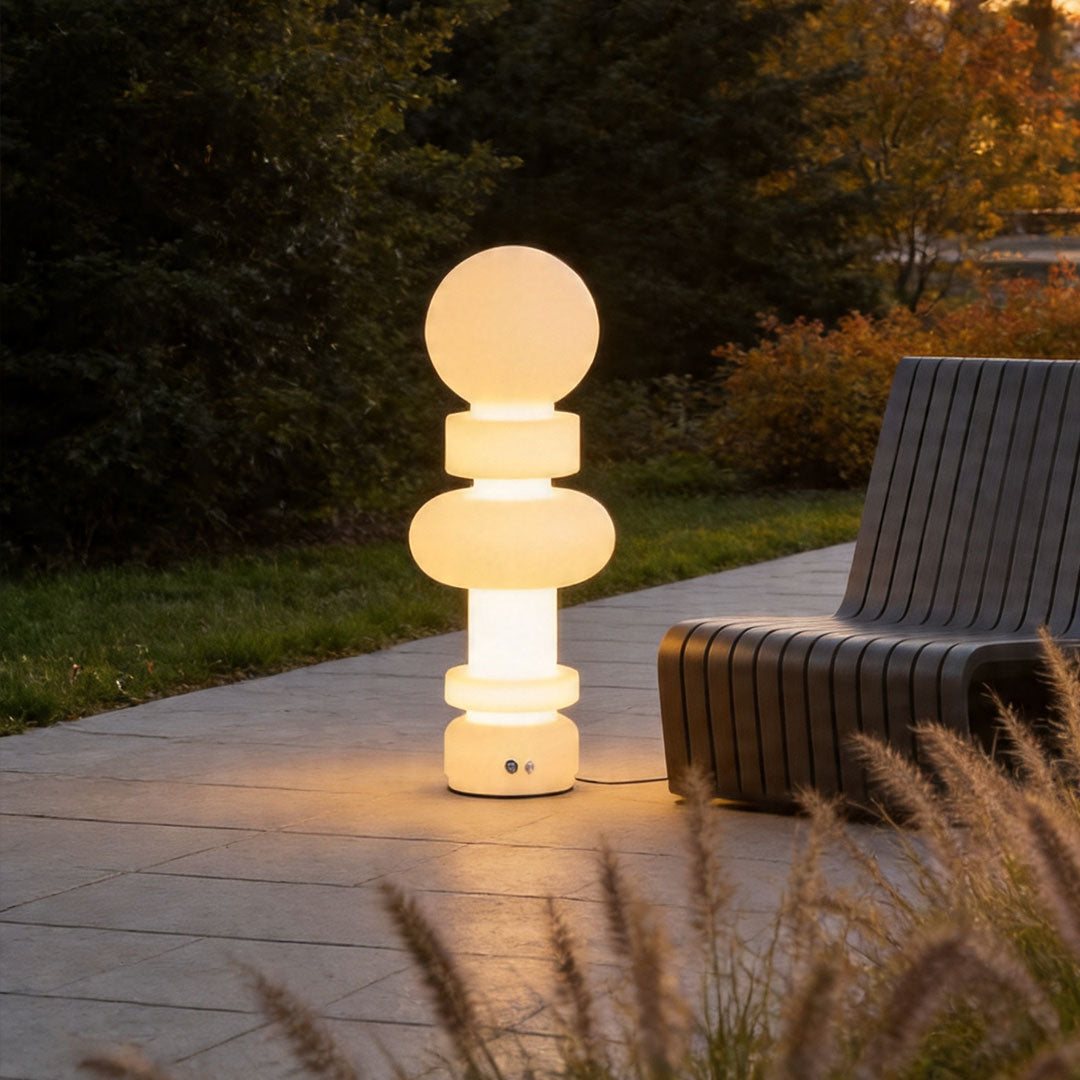 Modern outdoor floor lamps beside contemporary seating area with artistic glowing exterior design.