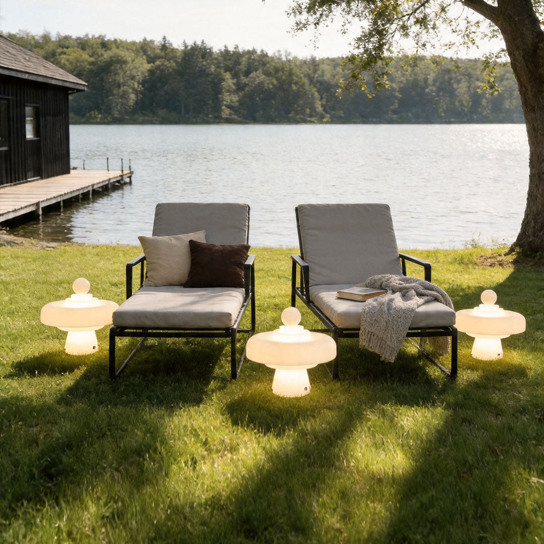 Modern outdoor floor lamps arranged beside lakeside lounge chairs creating warm ambient lighting.