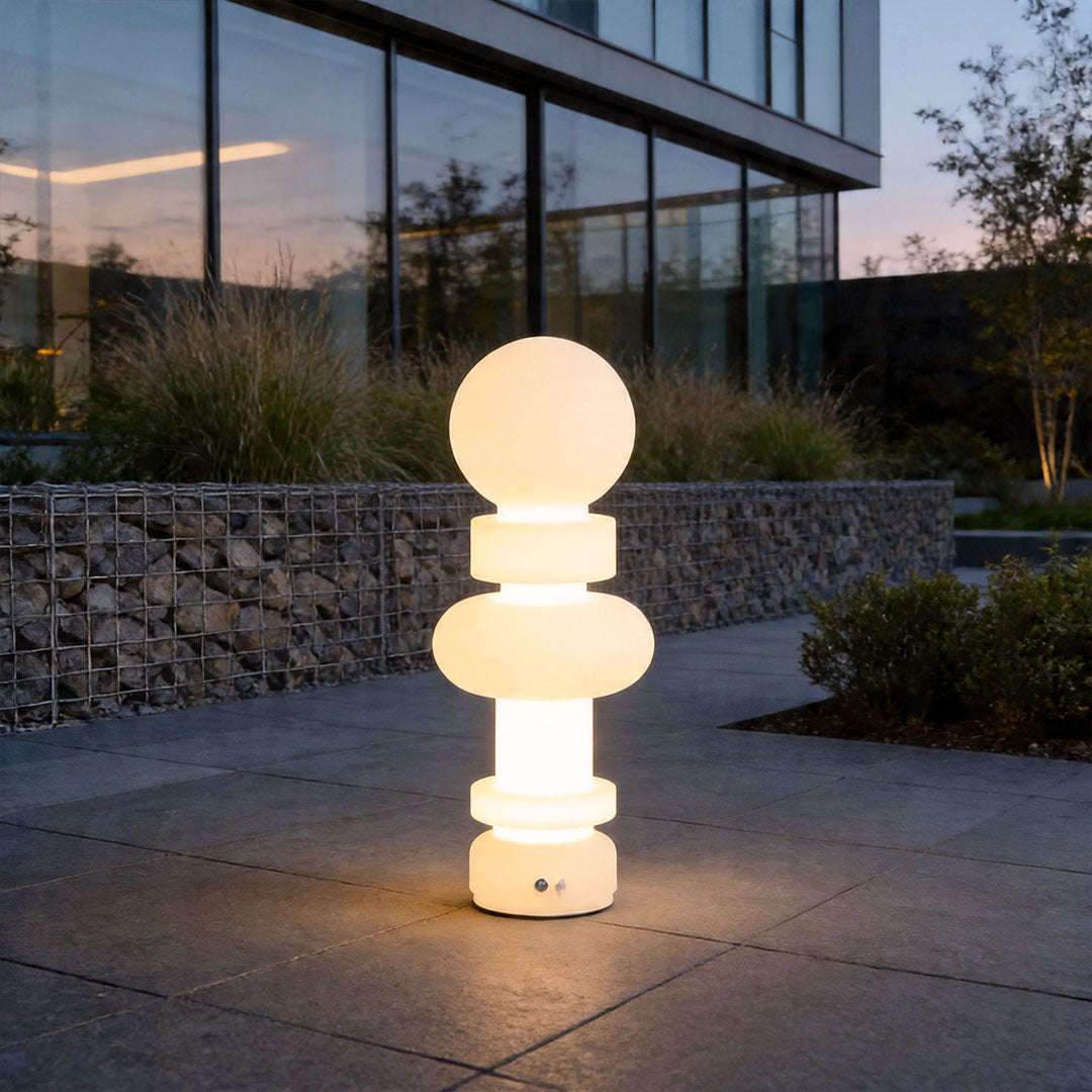 Modern outdoor floor lamps illuminating luxury patio walkway with sculptural glowing design at dusk.