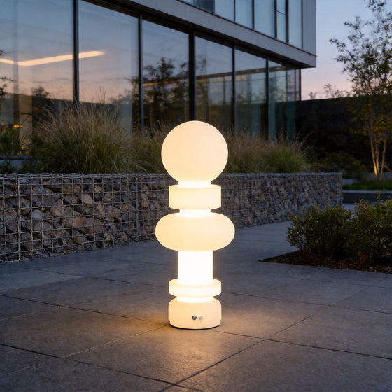 Modern outdoor floor lamps illuminating luxury patio walkway with sculptural glowing design at dusk.