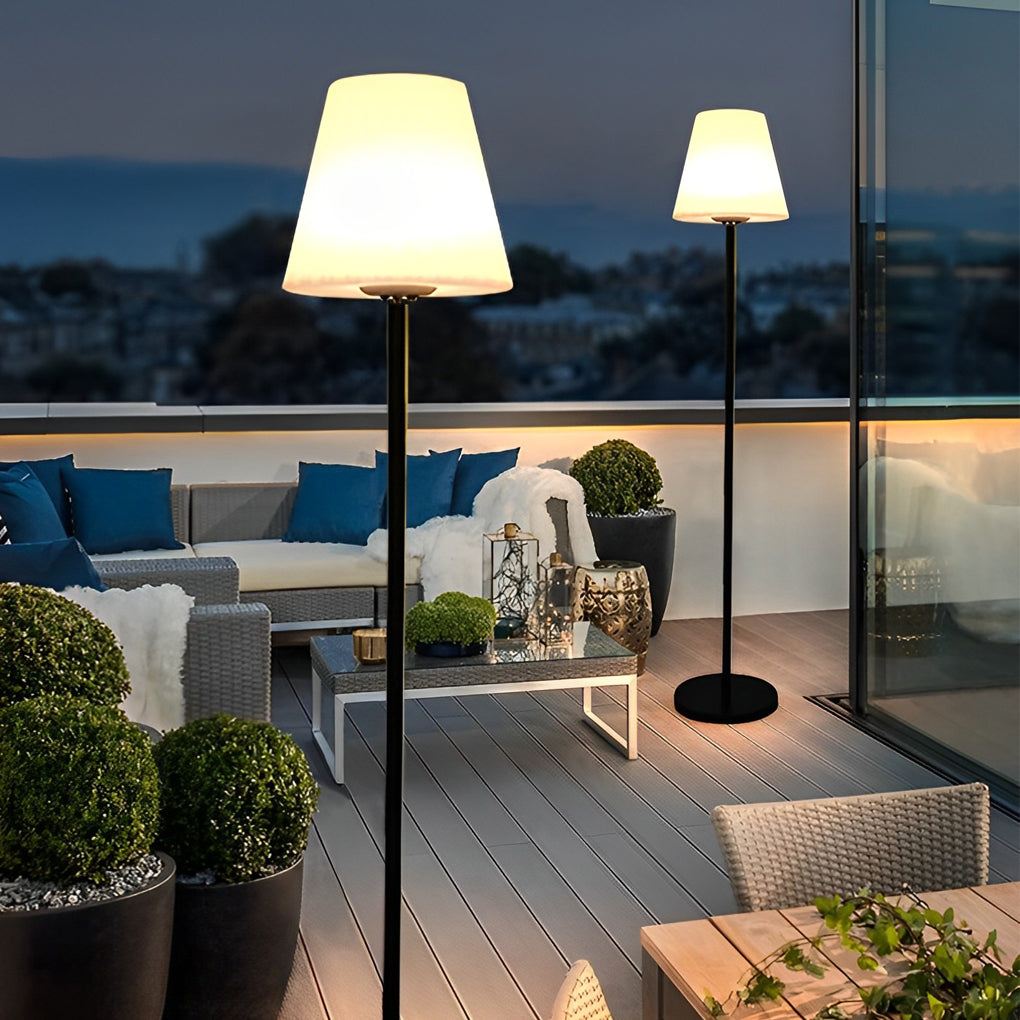 Pair of modern outdoor floor lamps creating a warm ambiance on a wooden deck with lounge chairs.
