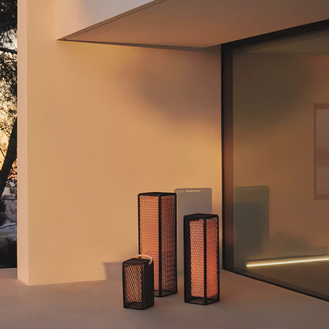 Modern outdoor lantern group placed beside a contemporary home entrance, emitting warm ambient light.