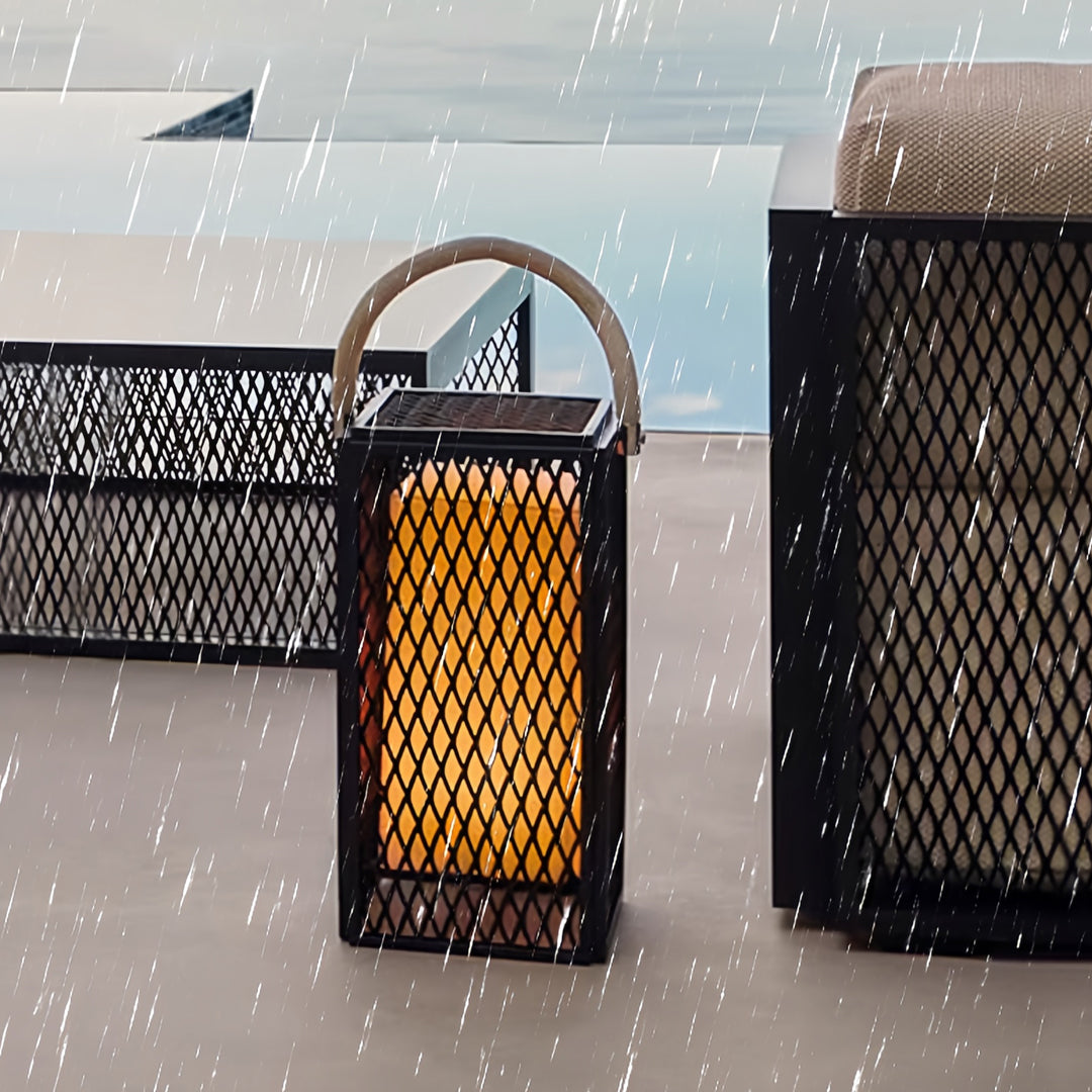 Handle-style modern outdoor lantern glowing warmly on a snowy deck with coastal scenery.