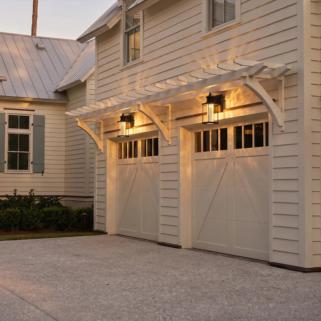 Modern outdoor lantern wall sconce lighting a carriage-style garage exterior with a warm welcoming glow.