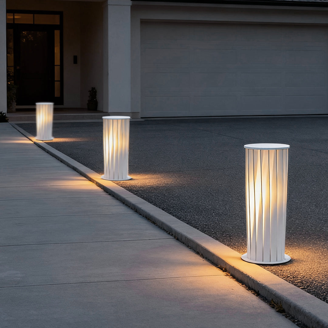 Modern outdoor lanterns installed along green lawn edge creating warm pathway lighting effect.