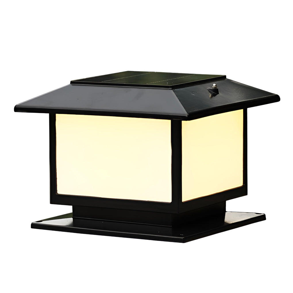 Modern outdoor pillar light with a black metal frame and frosted glass, providing a warm glow in a garden landscape.