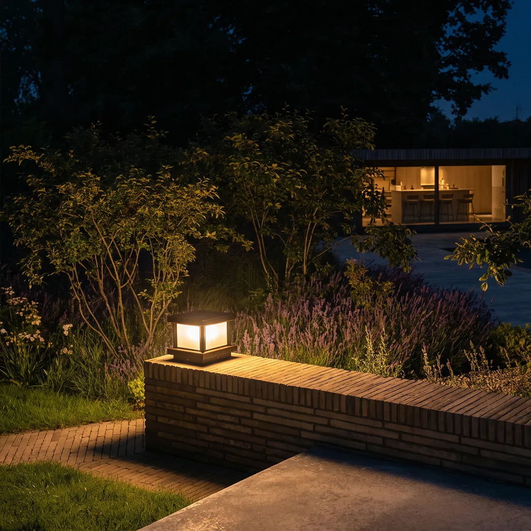 Modern outdoor pillar light with warm glow on brick garden wall at night