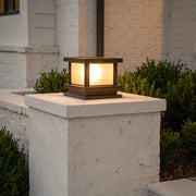 Modern outdoor pillar light with warm glow on concrete column beside home entrance