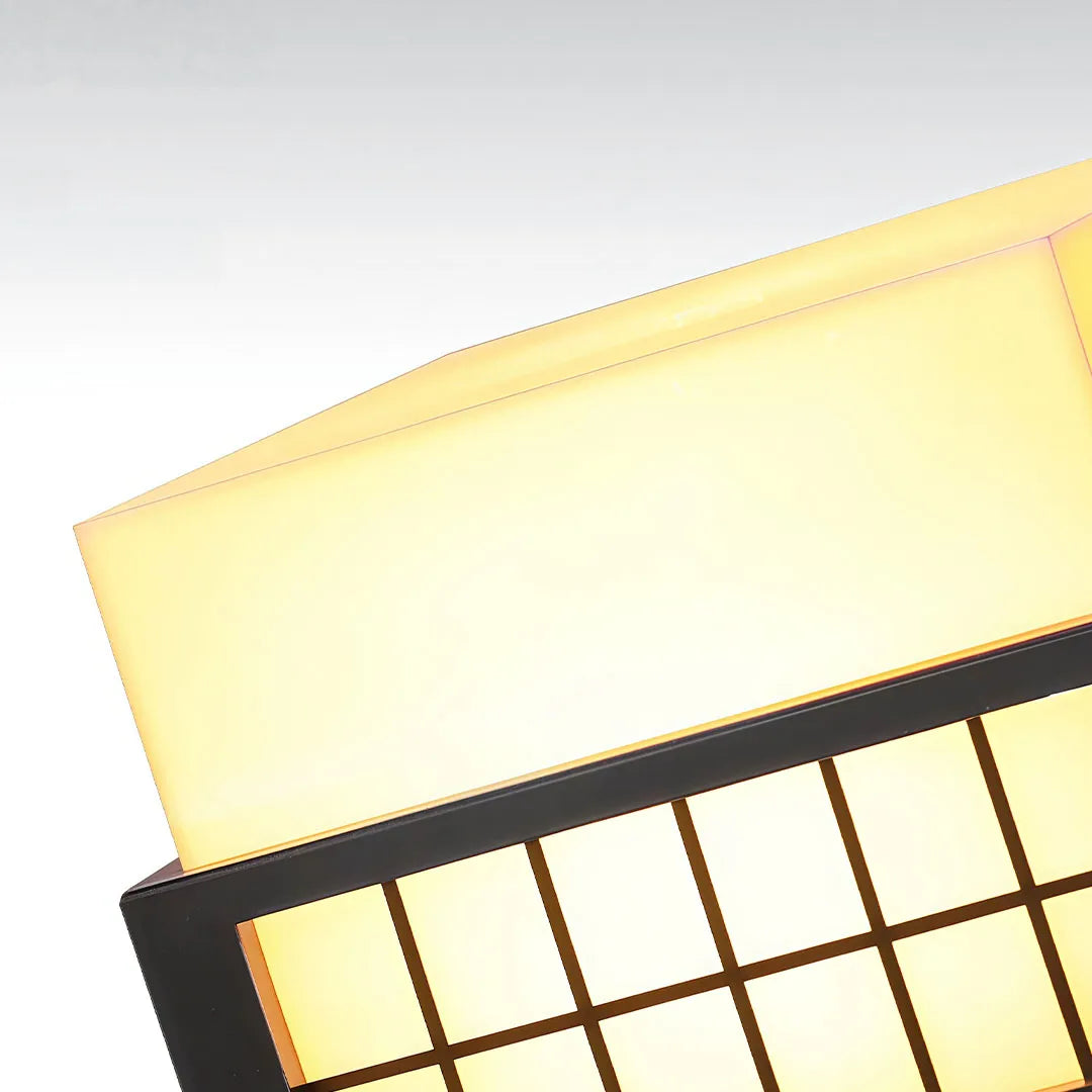 Close-up of modern outdoor pillar lights highlighting the illuminated diffuser and geometric frame design.