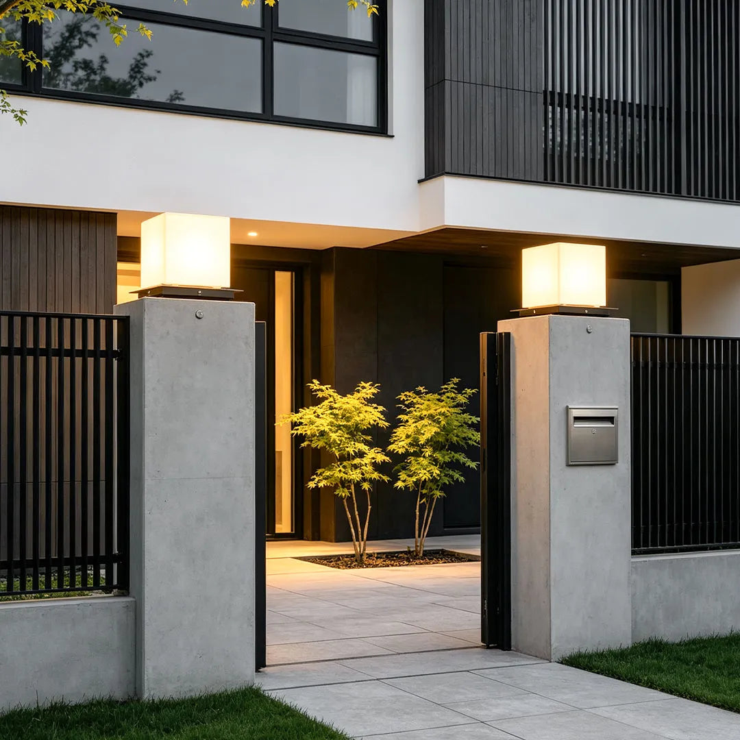 Modern outdoor pillar lights installed on concrete gate columns, providing a sleek and balanced outdoor lighting design.