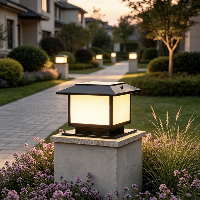Modern outdoor pillar lights mounted on a concrete gate post beside a landscaped walkway at dusk.