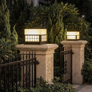 Modern outdoor pillar lights installed on stone gate columns with warm landscape illumination.