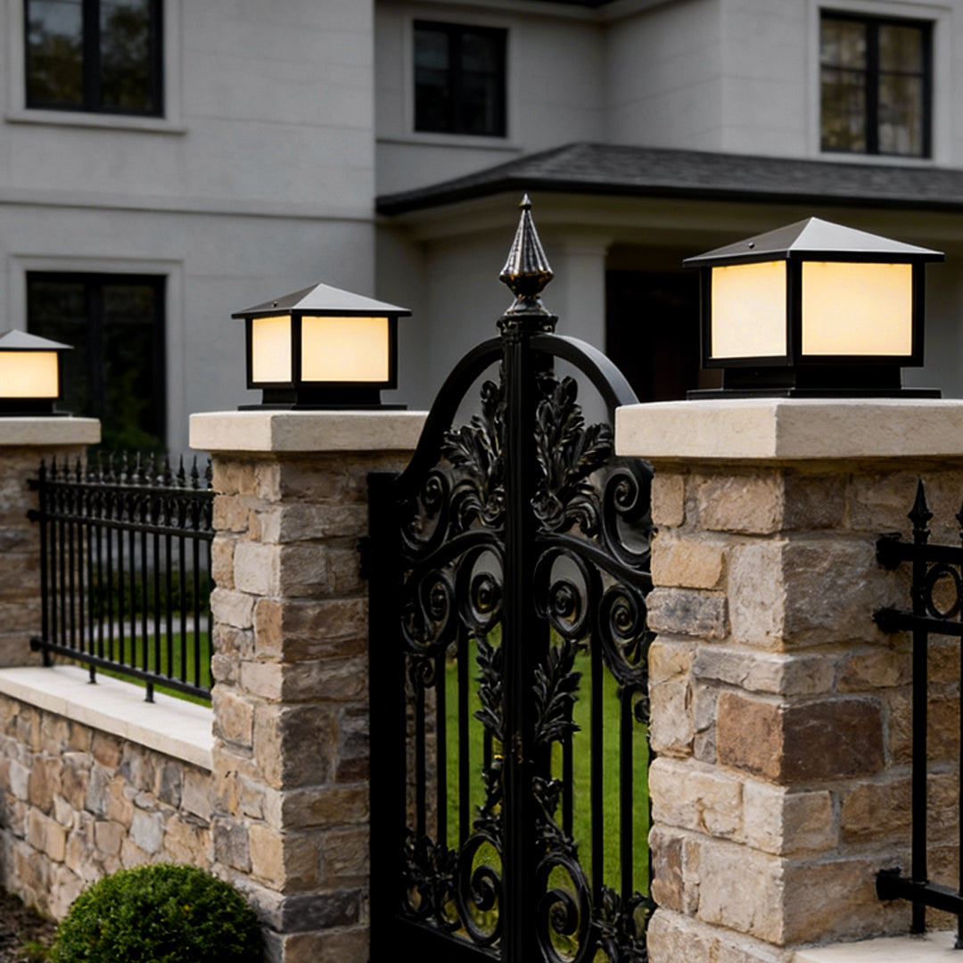 Modern outdoor pillar lights installed on gate pillars, providing warm ambient illumination for a residential driveway entrance.